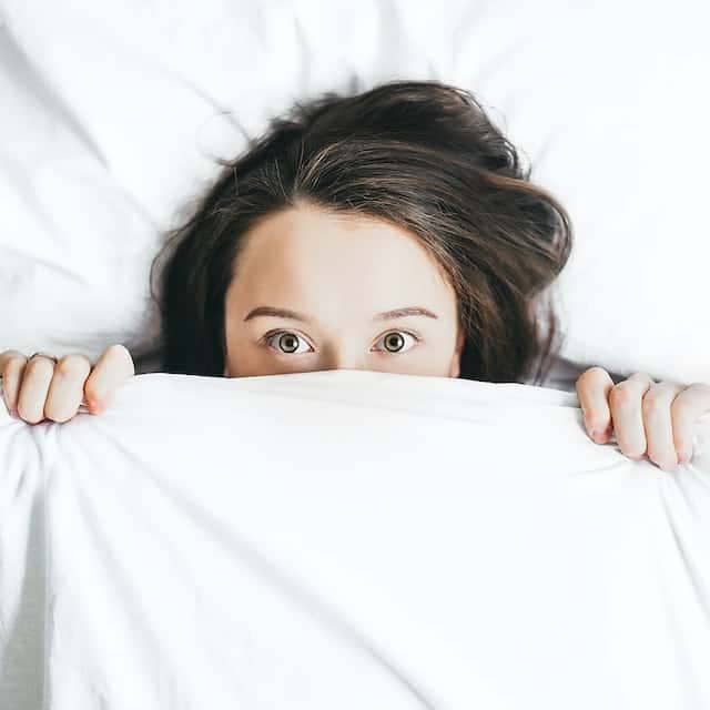 person hiding in bed ashamed